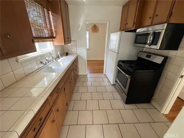 a kitchen with granite countertop a stove a sink and a microwave