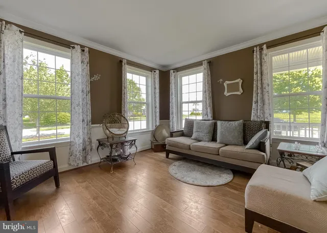 a living room with furniture kitchen view and a wooden floor