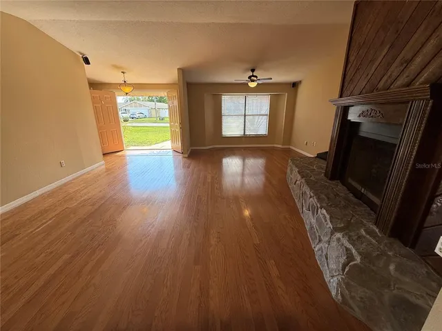 a view of empty room with wooden floor and fireplace