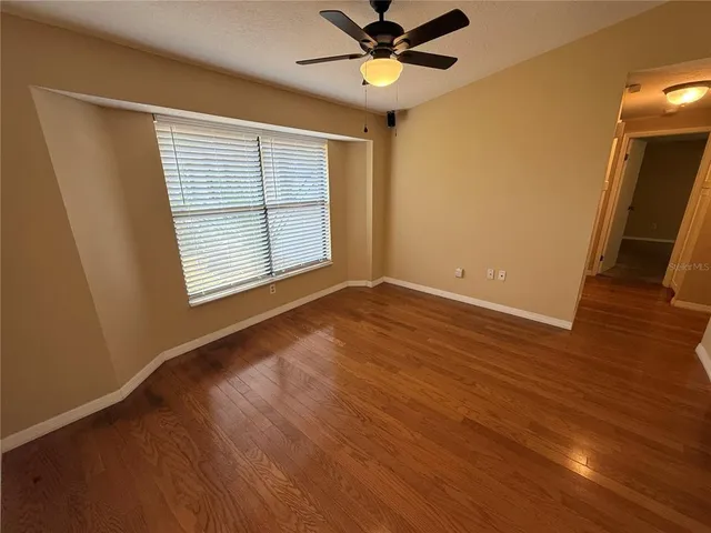 an empty room with windows and fan
