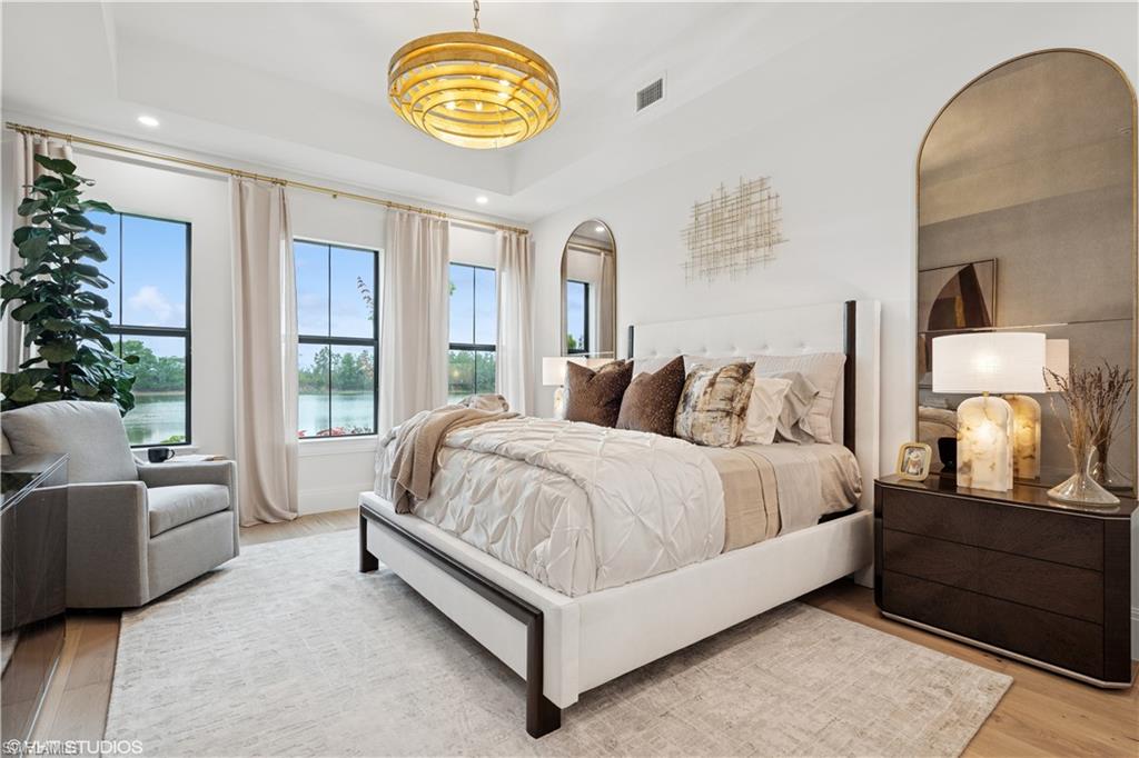 19781 Marino Lake Circle, Unit B4102 Miromar Lakes, FL 33913 - Photo 33 of 43 a spacious bedroom with a bed and a chandelier