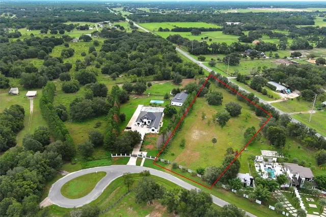 an aerial view of residential houses with outdoor space and trees