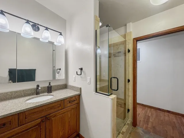 a bathroom with a granite countertop sink a toilet a mirror and shower
