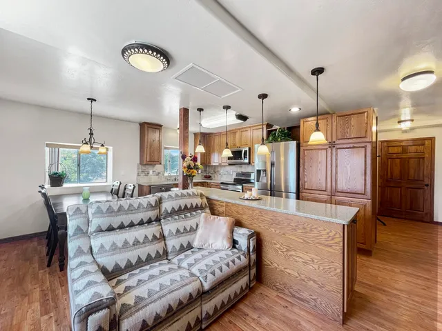 a large living room with stainless steel appliances kitchen island granite countertop furniture and a wooden floor