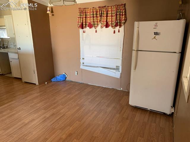 17610 Hanover Road Colorado Springs, CO 80928 - Photo 16 of 16 Kitchen with backsplash, white cabinetry, white refrigerator, and hardwood / wood-style floors