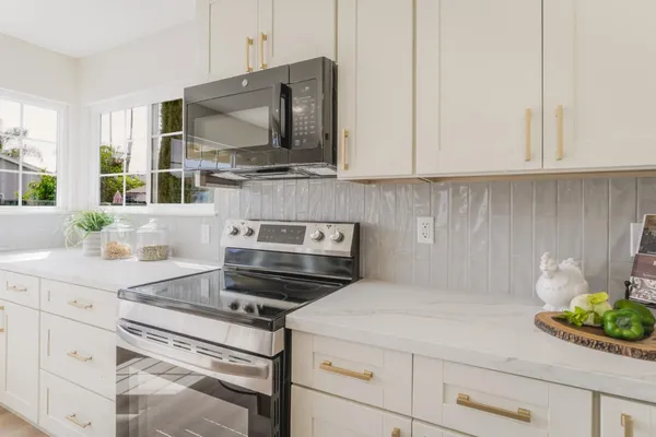 a kitchen with stainless steel appliances windows and a flat screen tv