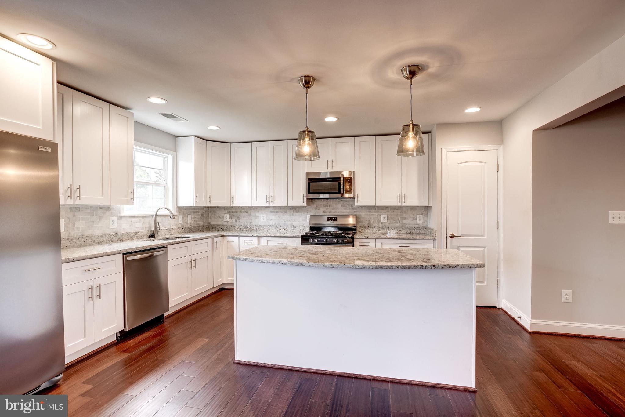 4121 Lees Corner Road Chantilly, VA 20151 - Photo 10 of 28 a kitchen with stainless steel appliances granite countertop a sink a stove a refrigerator and island with wooden floor