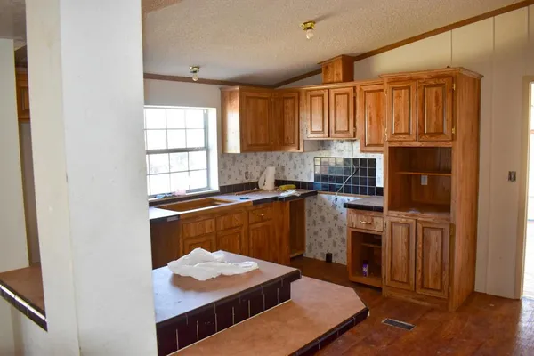 a kitchen with granite countertop a stove cabinets and wooden floor