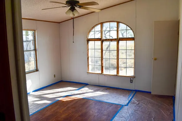 an empty room with wooden floor fan and windows