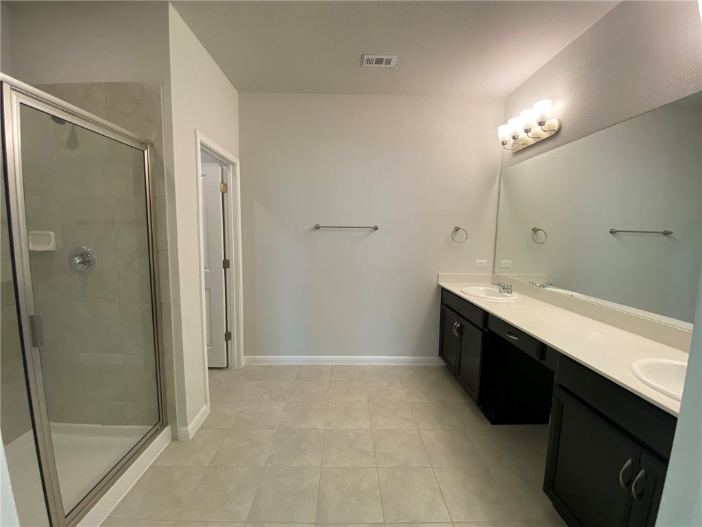 384 Gaida Loop Georgetown, TX 78628 - Photo 11 of 20 This Primary bathroom is extra large boasting walking shower, separate restroom, tile flooring and surround, and dual vanities.