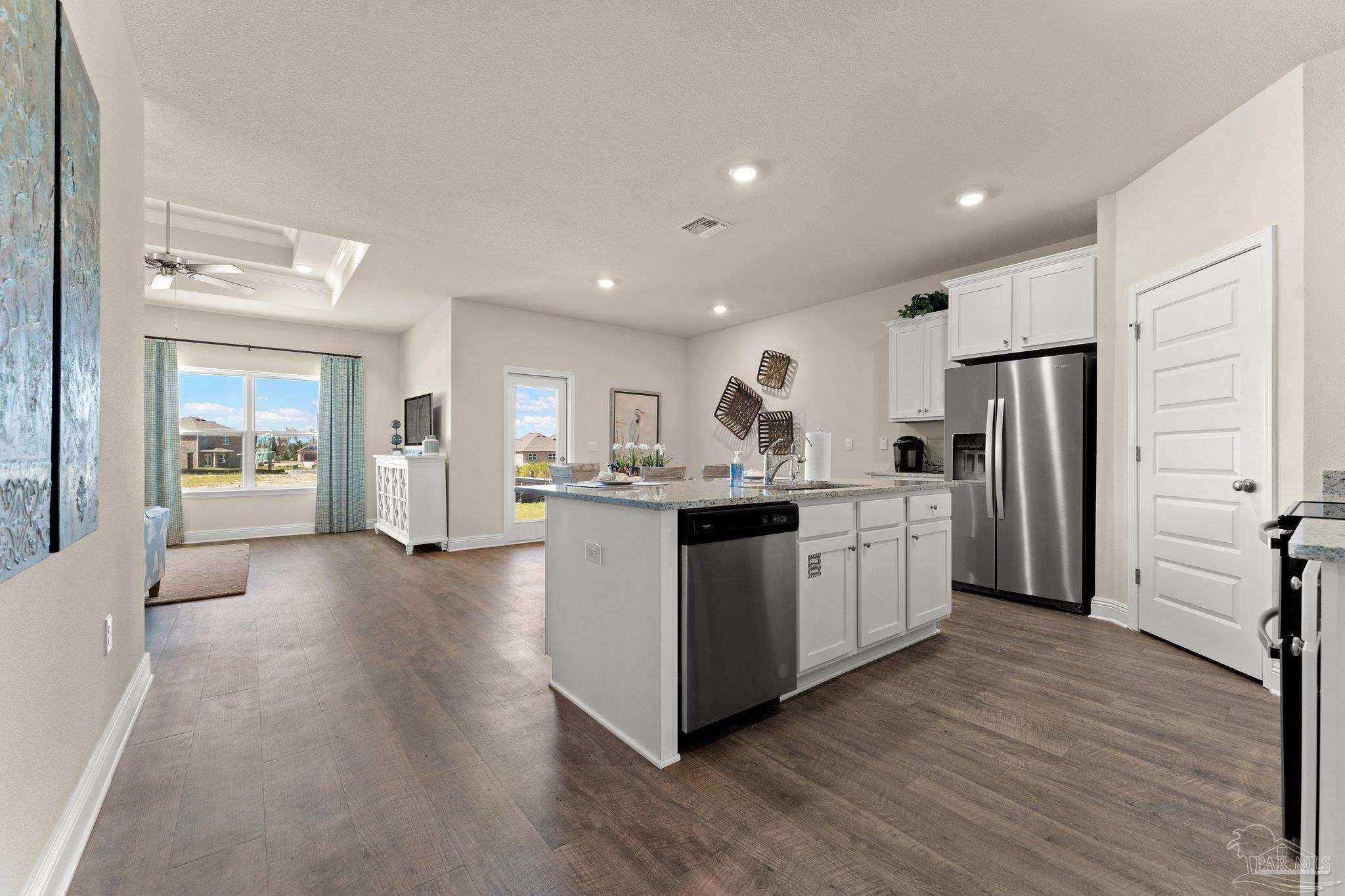 4946 Snipe Road Pace, FL 32571 - Photo 13 of 27 a kitchen with kitchen island white cabinets stainless steel appliances and wooden floor