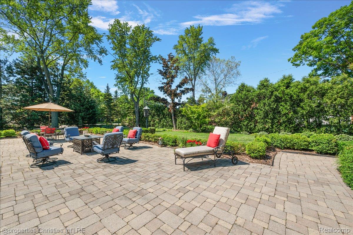 135 Clifton Road Bloomfield Hills, MI 48301 - Photo 70 of 77 Expansive paver patio featuring multiple seating areas, surrounded by mature trees and lush landscaping