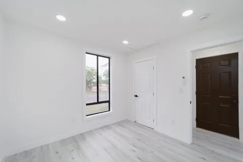 an empty room with wooden floor and windows