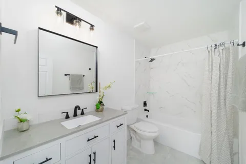 a bathroom with a granite countertop sink a toilet and a mirror