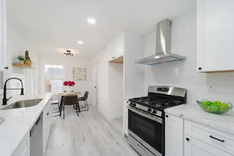 a kitchen with stainless steel appliances a white table chairs and a stove