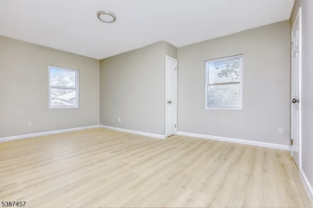 a view of an empty room with window and wooden floor