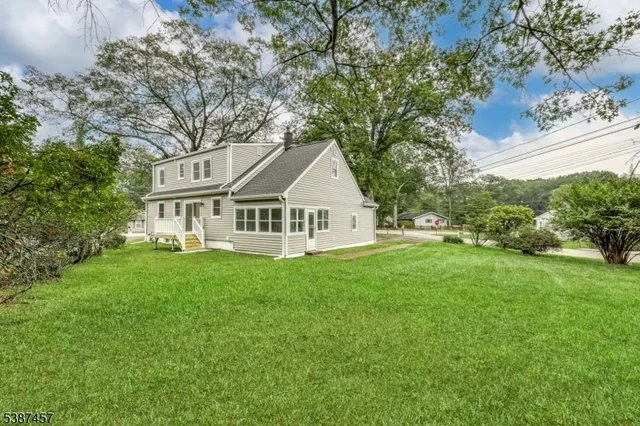 a view of a house with a big yard plants and large trees