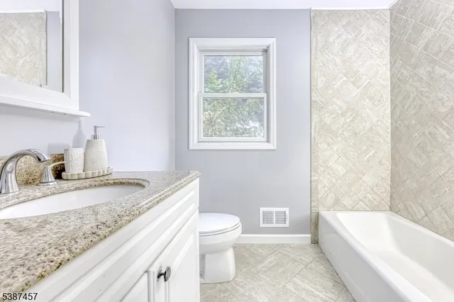 a bathroom with a granite countertop sink a toilet and bathtub