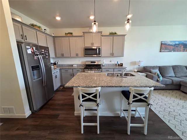 a kitchen with granite countertop a table chairs microwave and refrigerator