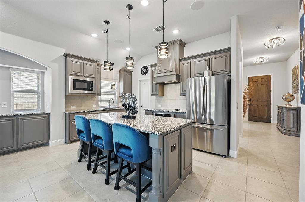 625 Ridgewater Trail Fort Worth, TX 76131 - Photo 3 of 27 Kitchen featuring freestanding refrigerator, black microwave, visible vents, custom exhaust hood, and a center island
