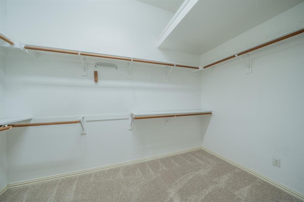 7517 Rodeo Drive Denton, TX 76208 - Photo 26 of 39 The primary bedroom closets includes a variety of hanging & shelf spaces and even an off-season clothes rack.