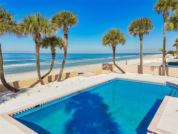 a view of a swimming pool with a lawn chairs under an umbrella