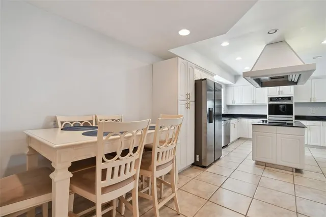a kitchen with stainless steel appliances kitchen island granite countertop a table chairs and a refrigerator