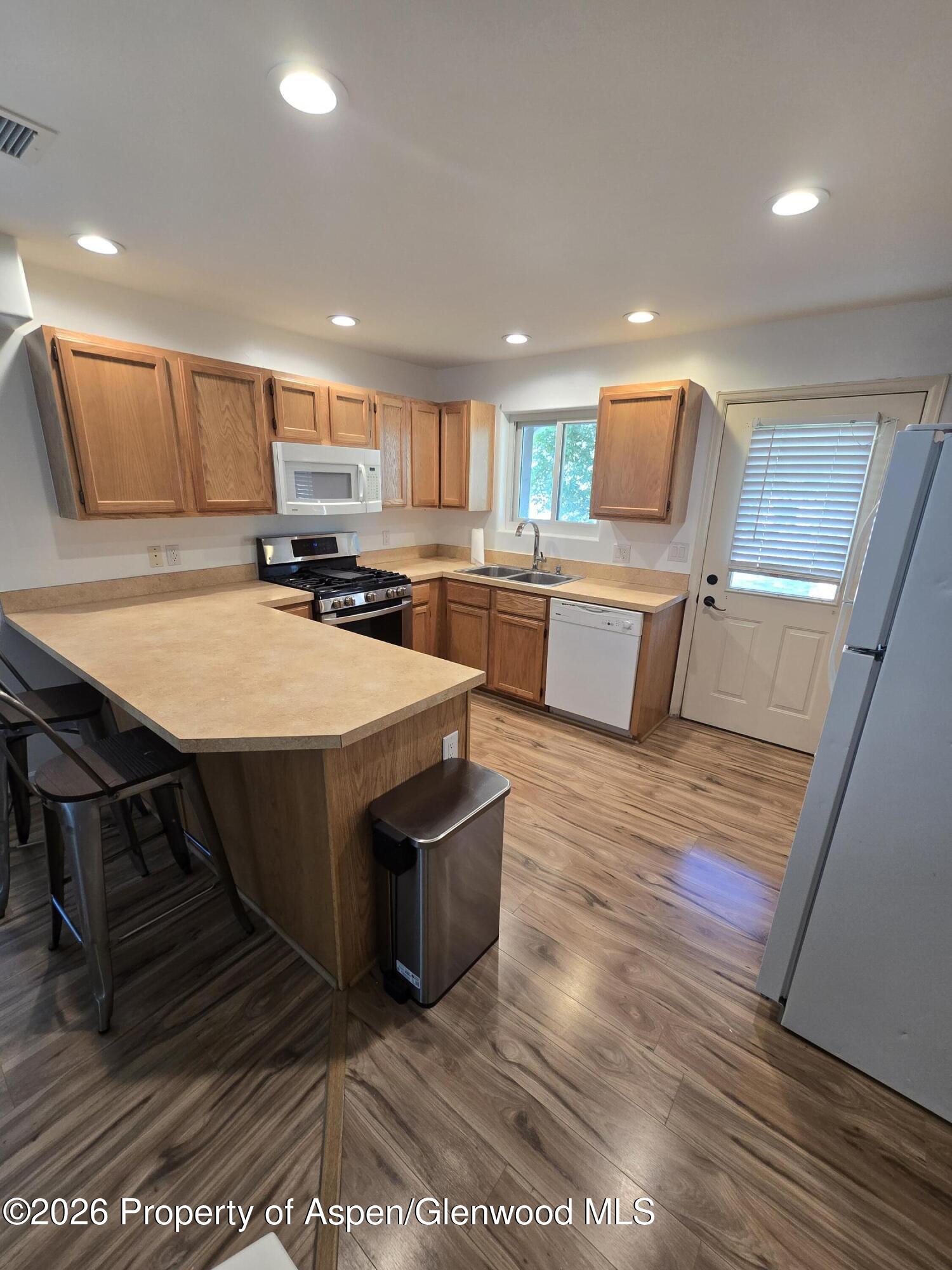 145 West 26th Street Rifle, CO 81650 - Photo 3 of 7 a kitchen with stainless steel appliances kitchen island granite countertop a table chairs sink and microwave