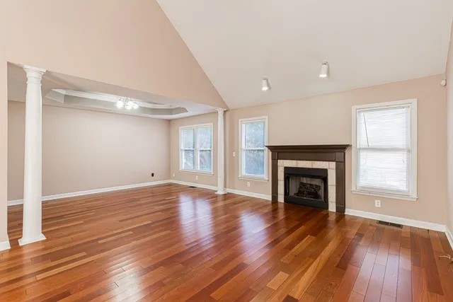 a view of an empty room with wooden floor fireplace and a window