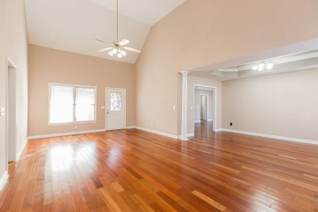 a view of an empty room with wooden floor and a window