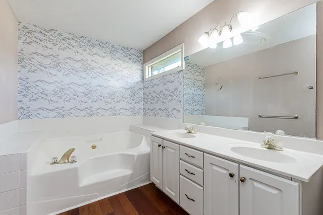 a bathroom with a tub a sink and mirror