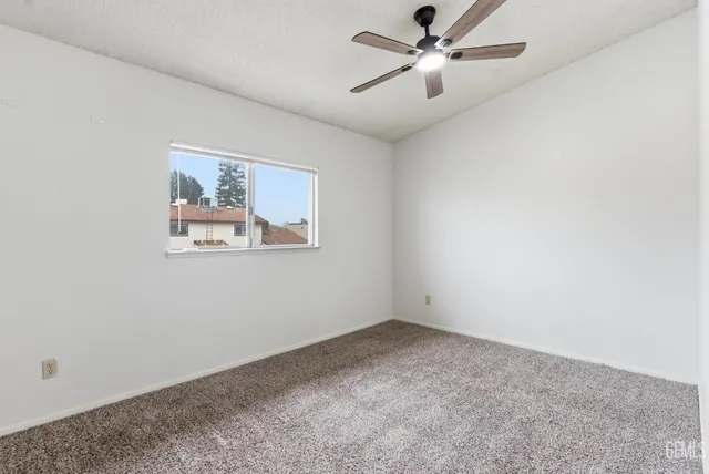 an empty room with a ceiling fan and a window