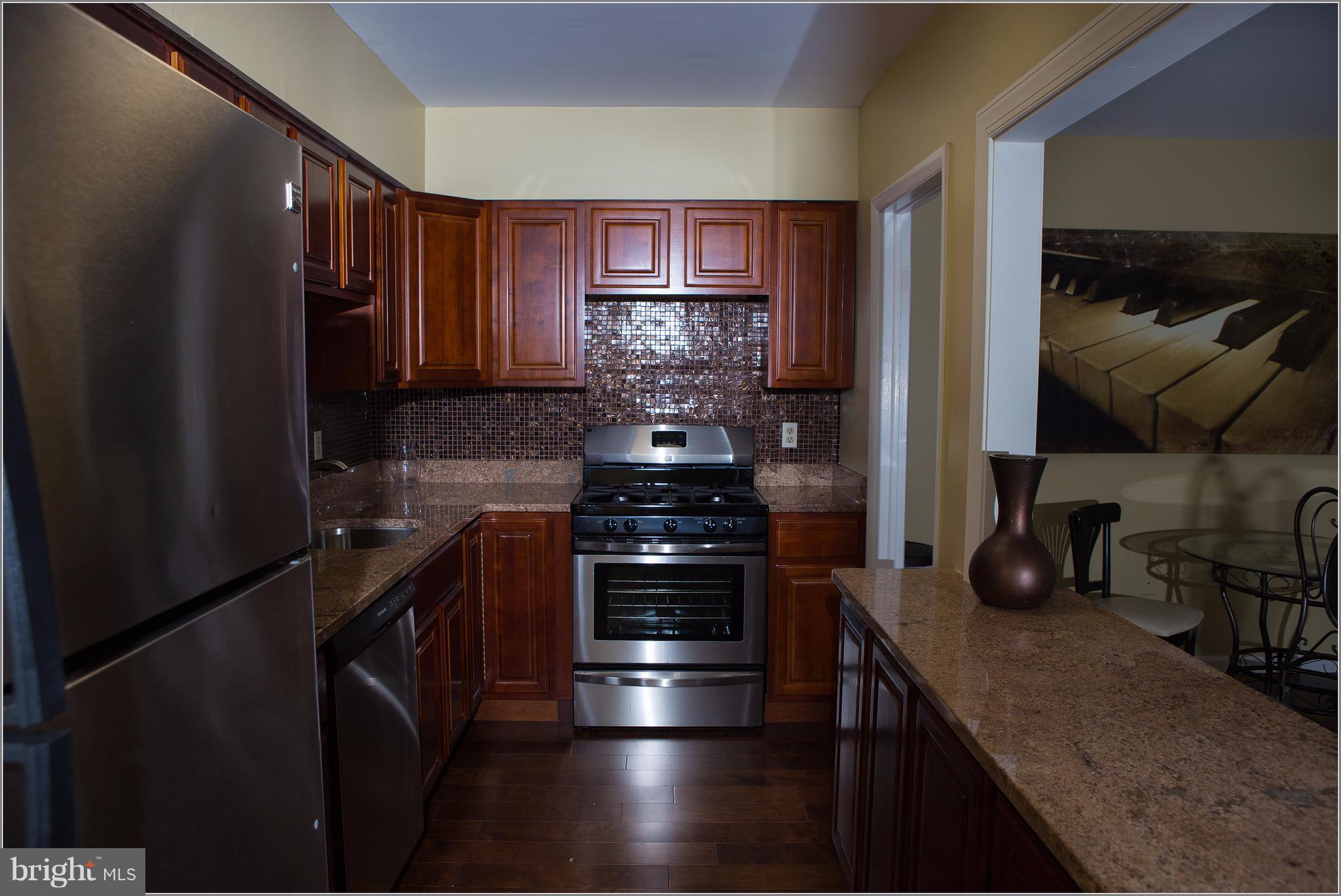 21 Hamill Road, Unit 21F Baltimore, MD 21210 - Photo 5 of 28 a kitchen with granite countertop a stove and a refrigerator