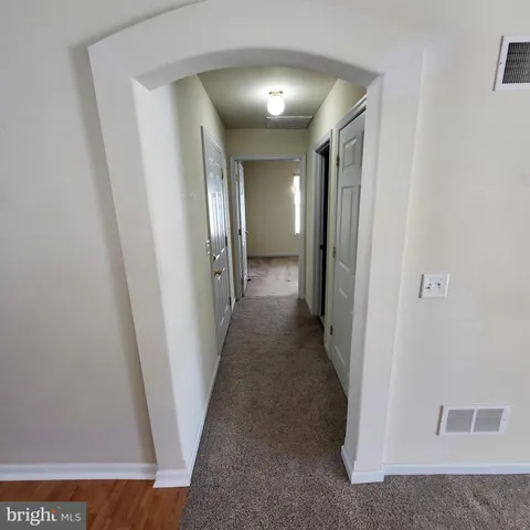 a view of a hallway with wooden floor and closet