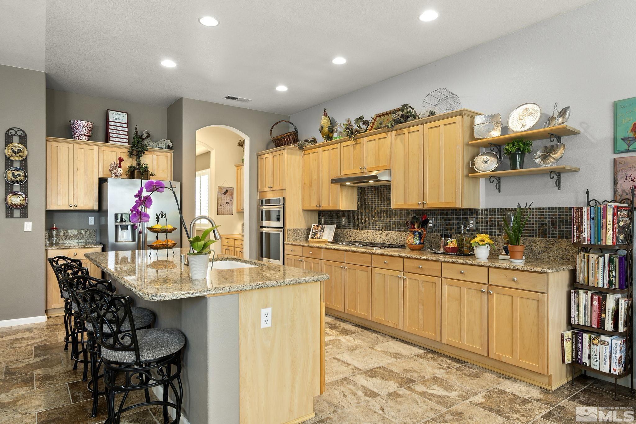 1585 Bethal Court Reno, NV 89521 - Photo 10 of 29 a kitchen with stainless steel appliances kitchen island granite countertop a table chairs and a refrigerator