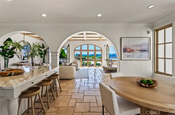 a living room with stainless steel appliances furniture a rug and a kitchen view