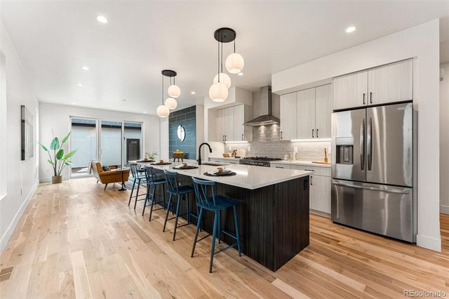 a kitchen with stainless steel appliances a stove a refrigerator a sink dishwasher and a dining table with wooden floor