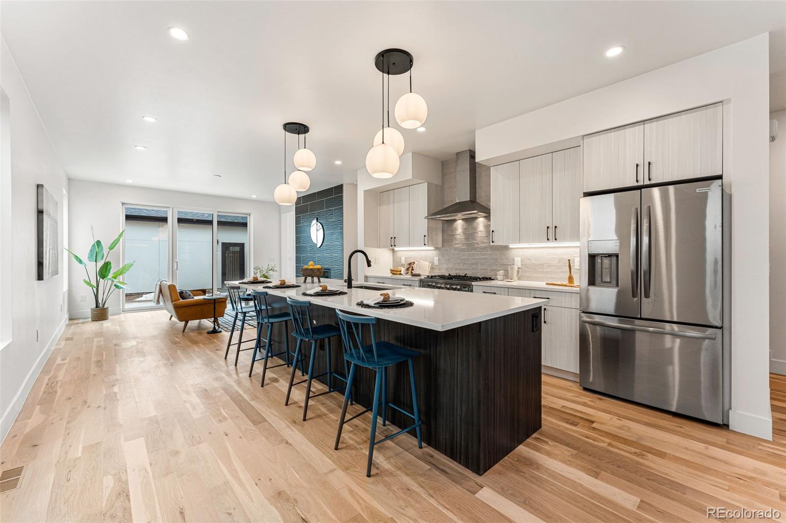 2410 South Bannock Street Denver, CO 80223 - Photo 11 of 40 a kitchen with stainless steel appliances a stove a refrigerator a sink dishwasher and a dining table with wooden floor