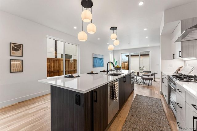a large kitchen with kitchen island a sink a stove and wooden floor