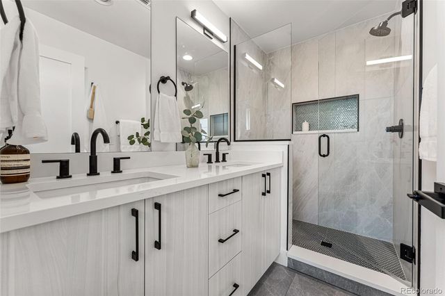 a bathroom with a double vanity sink mirror and shower