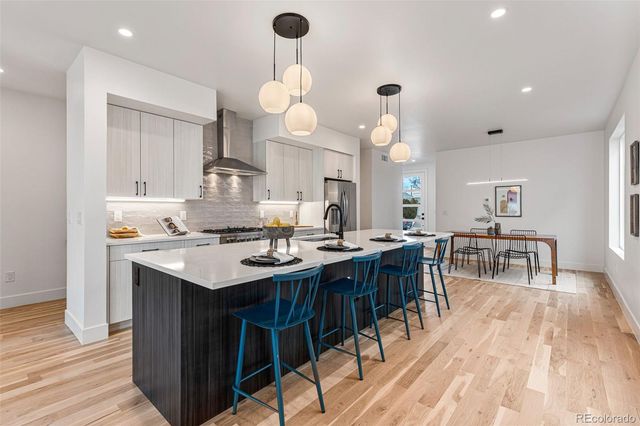 an open kitchen with a dining table chairs and white cabinets