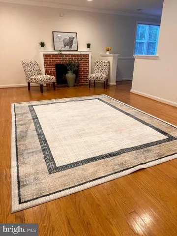 a view of an empty room with wooden floor and a fireplace
