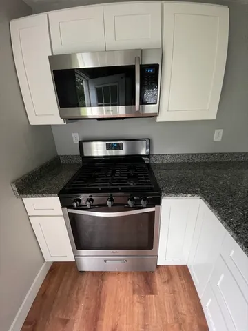 a kitchen with granite countertop a stove and a microwave