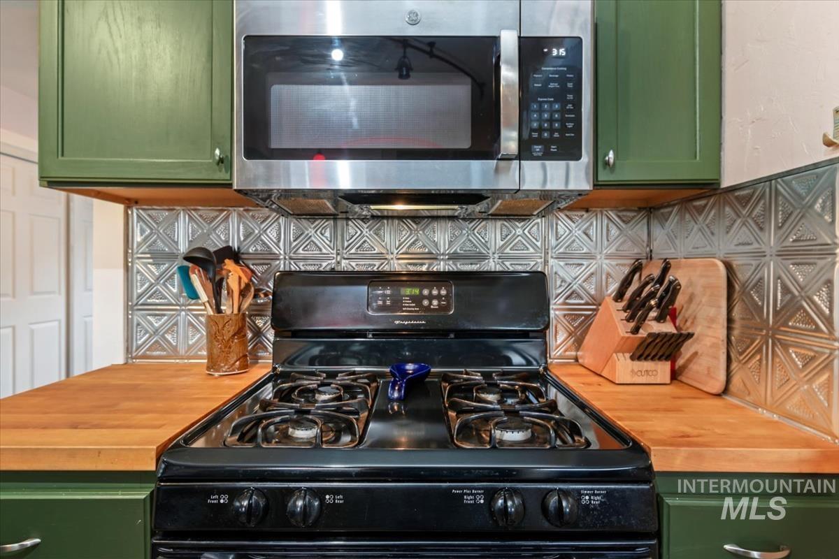 2837 Ona Street Boise, ID 83705 - Photo 17 of 26 Kitchen view of green cabinets, stainless steel microwave, black range with gas stovetop, and tasteful backsplash