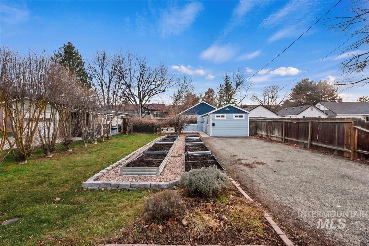 2837 Ona Street Boise, ID 83705 - Photo 2 of 26 View of yard featuring a vegetable garden, asphalt driveway, a residential view, and an outdoor structure