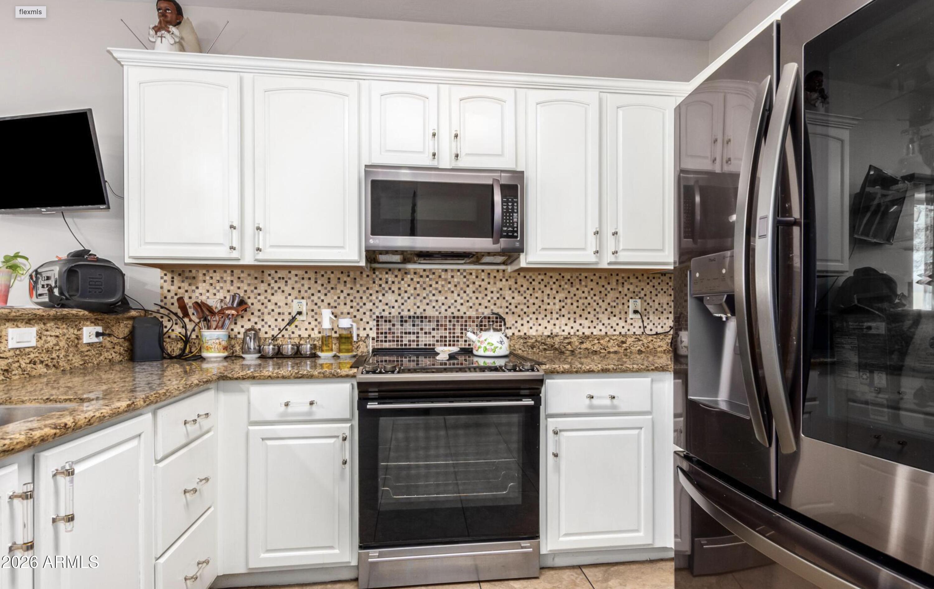 10225 West Camelback Road, Unit 12 Phoenix, AZ 85037 - Photo 9 of 19 a kitchen with stainless steel appliances granite countertop a stove microwave and refrigerator
