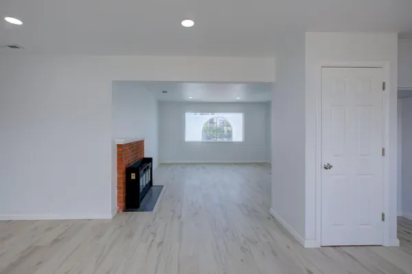 an empty room with wooden floor fireplace and windows