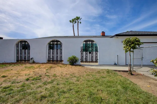 a view of a house with potted plants and wooden fence