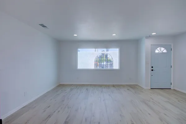 an empty room with wooden floor and windows