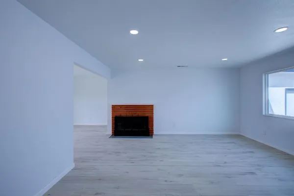a view of an empty room with a window and fire place